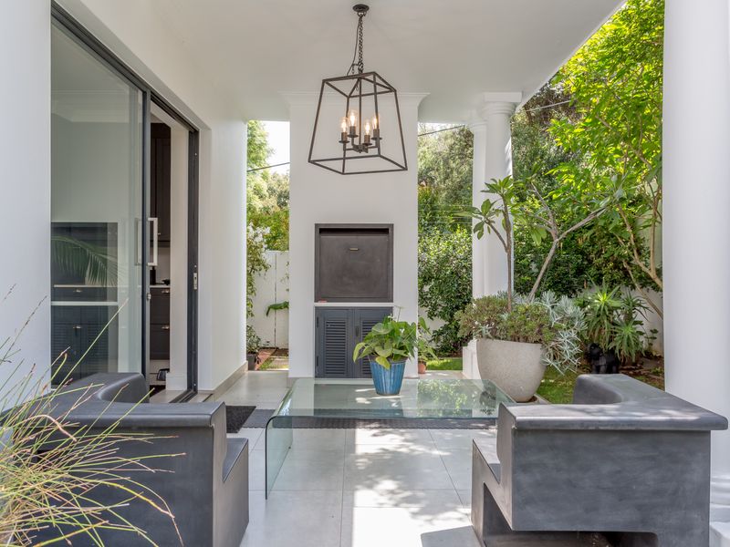 A covered patio featuring a built-in braai, tiled flooring, and elegant columns, providing a seamless transition to the garden area.