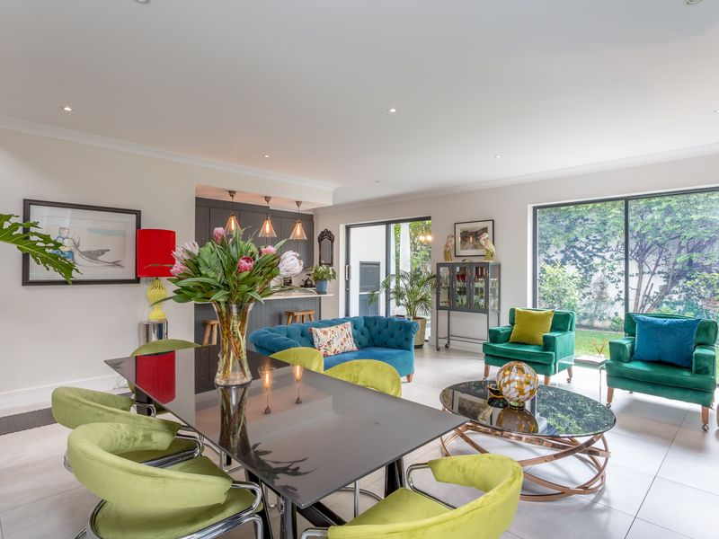 Spacious open-plan living and dining area featuring modern tiled floors, recessed lighting, and large sliding glass doors providing seamless access to the garden.