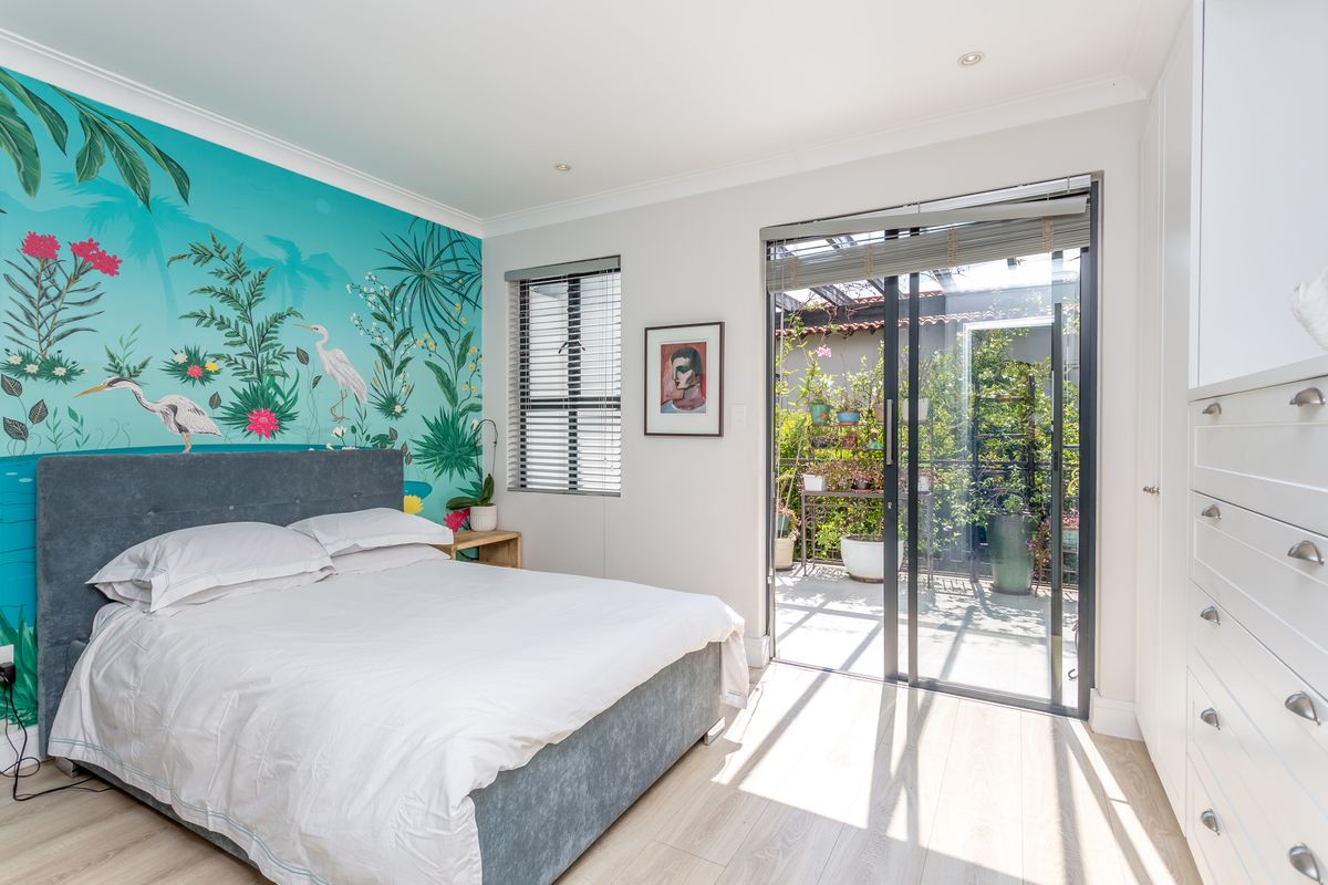 Bright bedroom featuring built-in cupboards, laminate flooring, and a sliding glass door providing direct access to a private patio area.