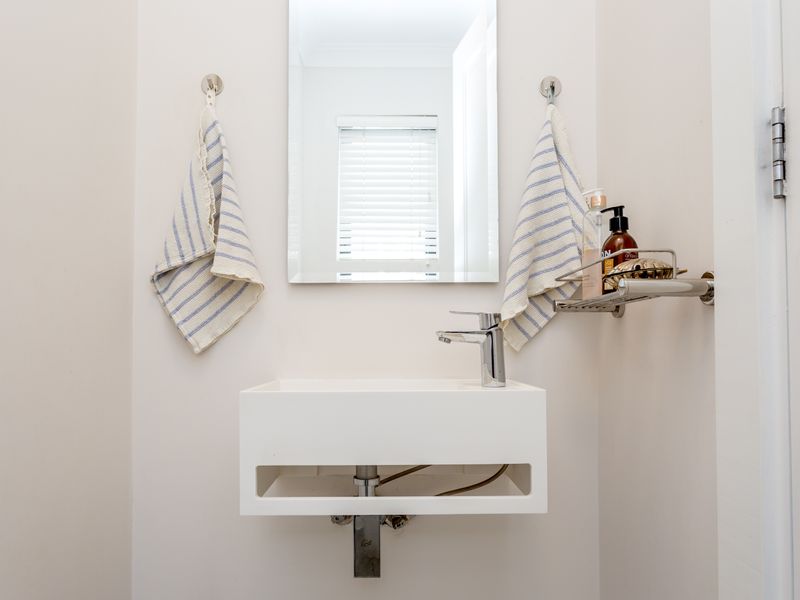 A compact guest bathroom featuring a modern wall-mounted basin, chrome mixer tap, and a clean, minimalist aesthetic.