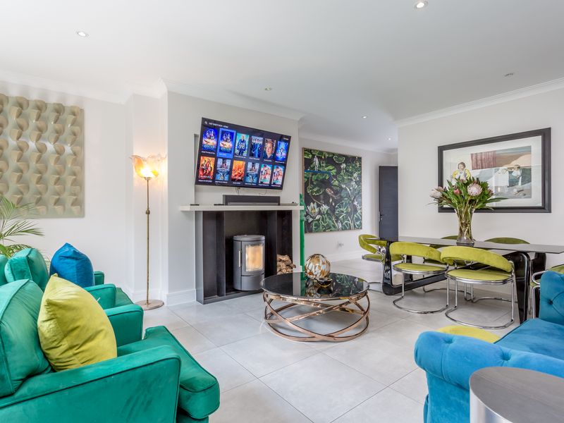 Spacious open-plan living and dining area featuring modern tiled flooring, recessed lighting, and a contemporary built-in fireplace.