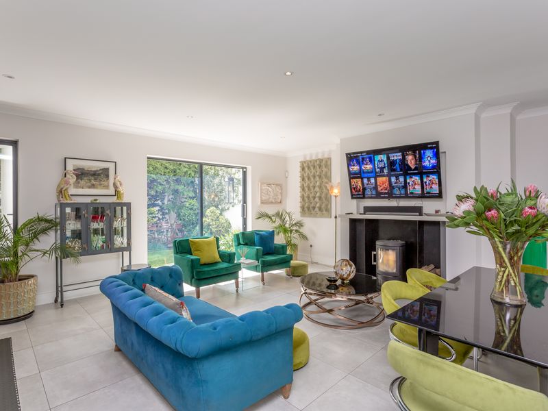 Spacious open-plan living area featuring a modern fireplace, large sliding glass doors providing garden access, and neutral tiled flooring throughout.