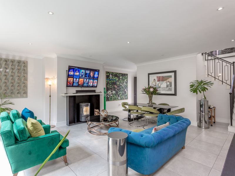 Spacious open-plan living and dining area featuring modern tiled flooring, a built-in fireplace, and a contemporary staircase with metal balustrades.