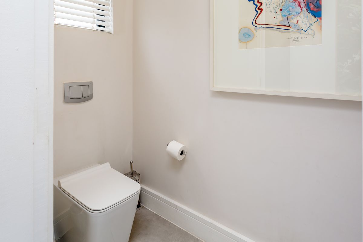 A clean and modern guest cloakroom featuring a wall-hung toilet with a concealed cistern and neutral finishes.