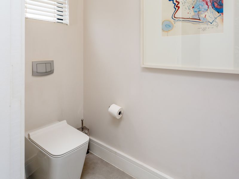 A clean and modern guest cloakroom featuring a wall-hung toilet with a concealed cistern and neutral finishes.
