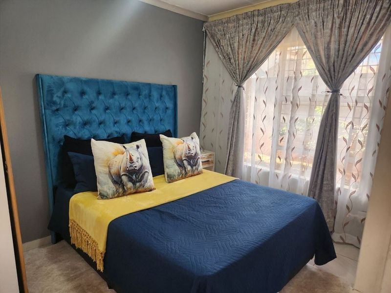A well-maintained bedroom featuring tiled flooring and large windows with installed curtain rails, providing a comfortable and functional living space.