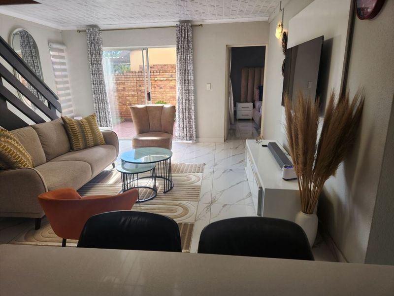 Open-plan living area featuring polished marble-look floor tiles, a textured ceiling, and a sliding glass door providing access to the rear patio.