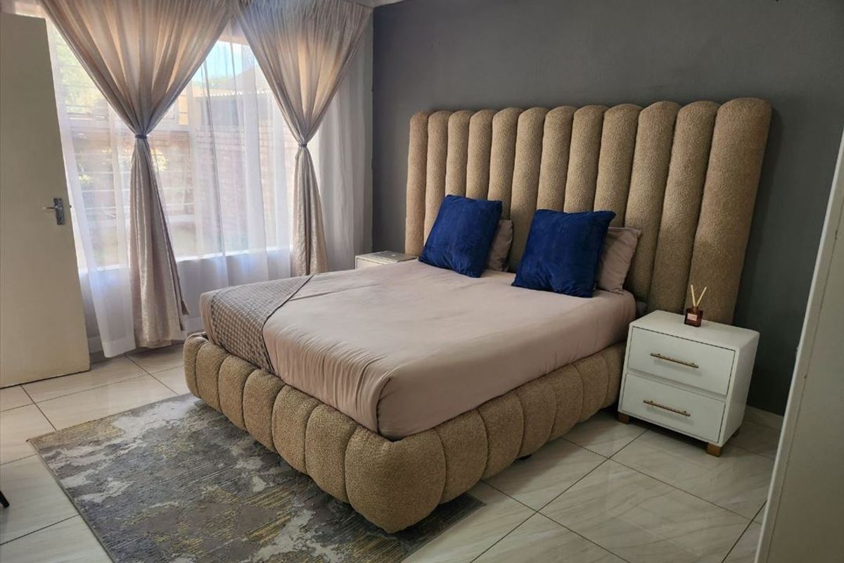 A well-maintained bedroom featuring tiled flooring, a neutral color palette, and an accent wall, providing a comfortable and functional living space.