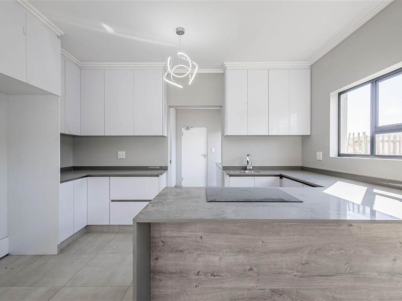 Modern kitchen featuring sleek white cabinetry, stone countertops, integrated hob, and tiled flooring in a clean, minimalist design.