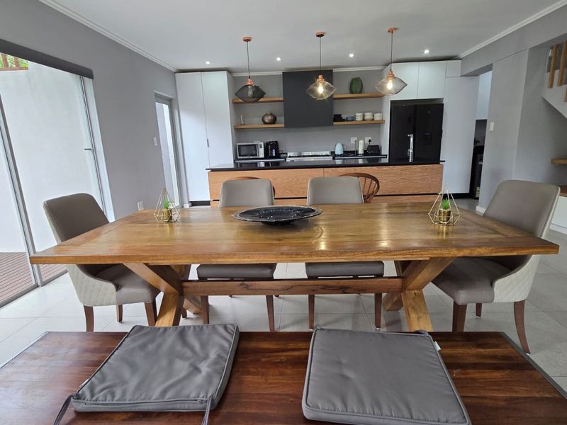 Open-plan living and dining area featuring a modern kitchen with built-in cabinetry, island, and direct access to the patio through sliding glass doors.