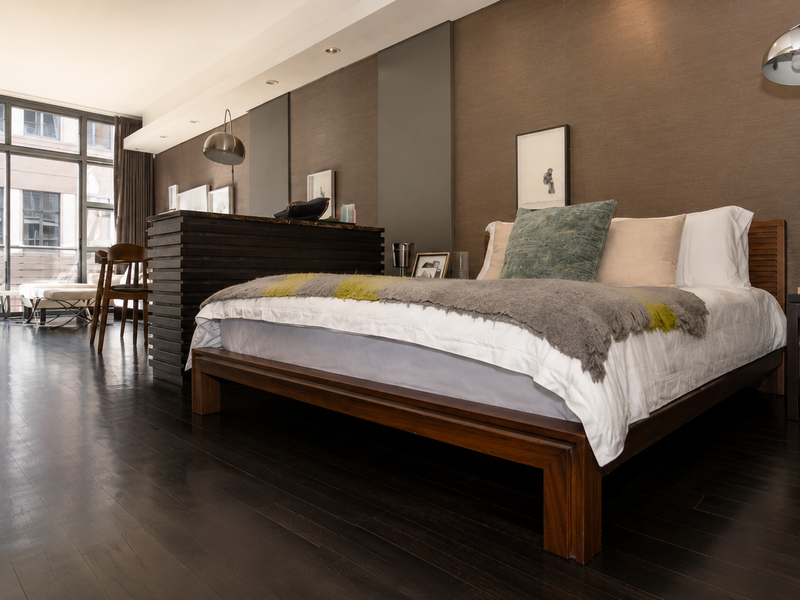 Spacious bedroom featuring dark hardwood flooring, a built-in room divider, and large sliding glass doors leading to a private balcony.