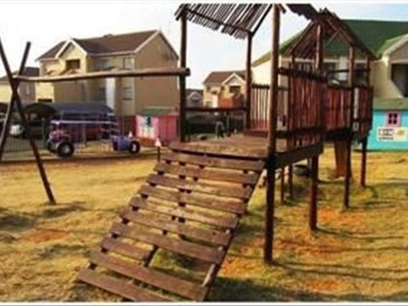 Communal garden area featuring a wooden playground structure set within a townhouse complex.