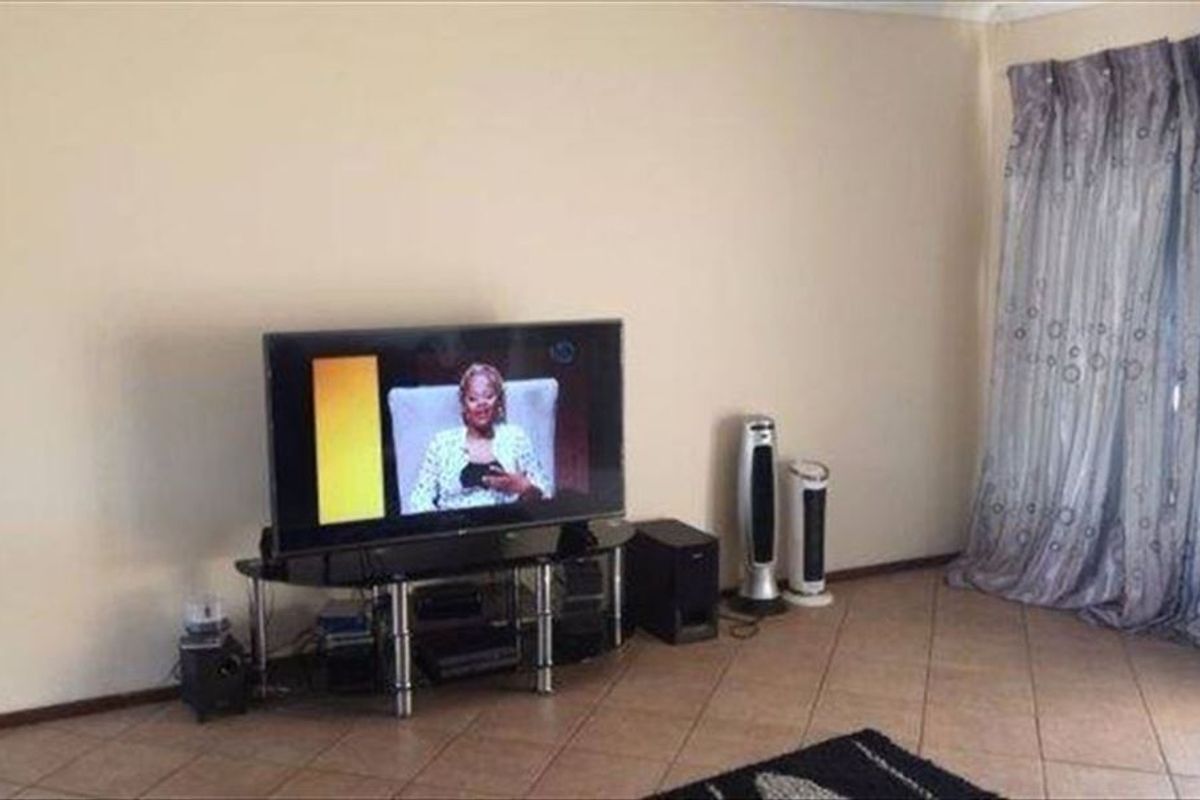 A living room area featuring tiled flooring and a sliding door with curtains, providing access to the exterior.