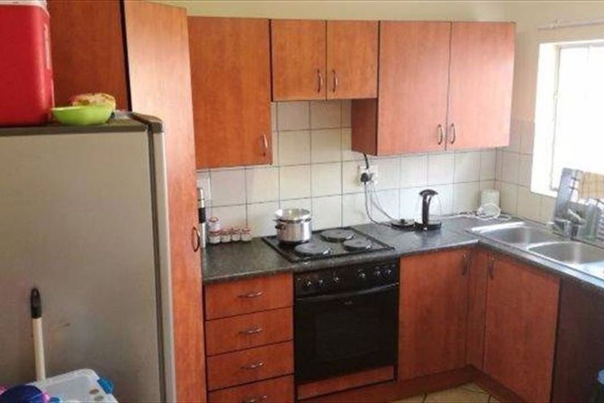 A compact kitchen featuring laminate cabinetry, a built-in oven with electric hob, and a double bowl sink with tiled backsplash.