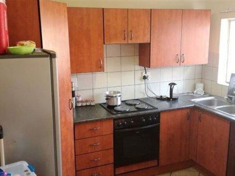 A compact kitchen featuring laminate cabinetry, a built-in oven with electric hob, and a double bowl sink with tiled backsplash.
