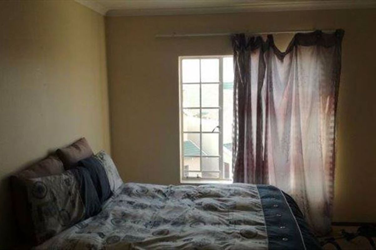 A standard bedroom featuring a window with security bars and neutral wall finishes.