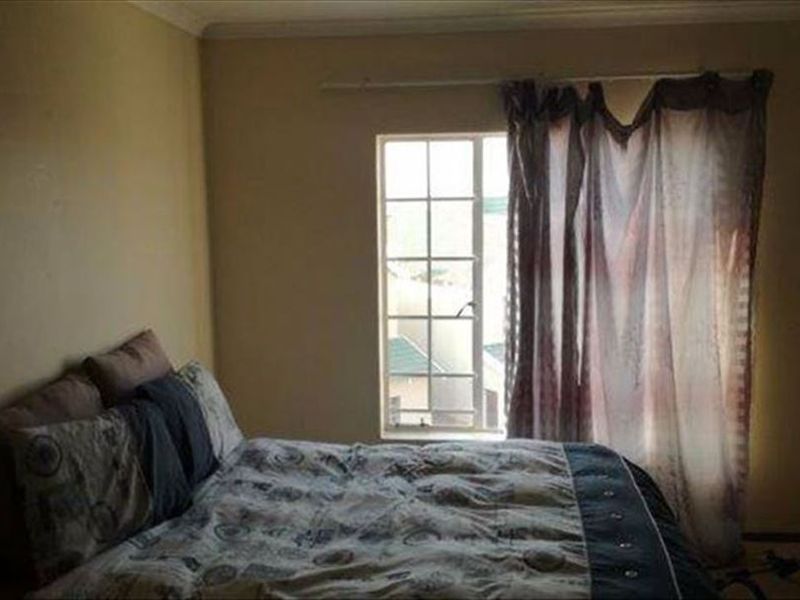A standard bedroom featuring a window with security bars and neutral wall finishes.