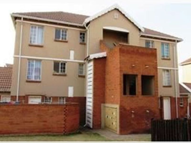 Rear view of a multi-story townhouse complex featuring brick and plaster facade, tiled roofing, and surrounding boundary walls.