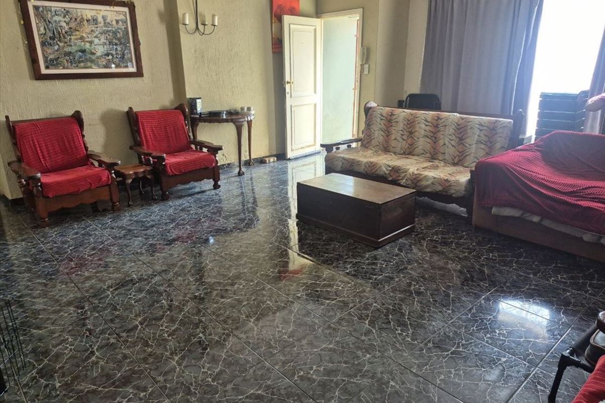Spacious living room featuring dark marble-effect tiled flooring and textured wall finishes, offering a functional layout with natural light access.