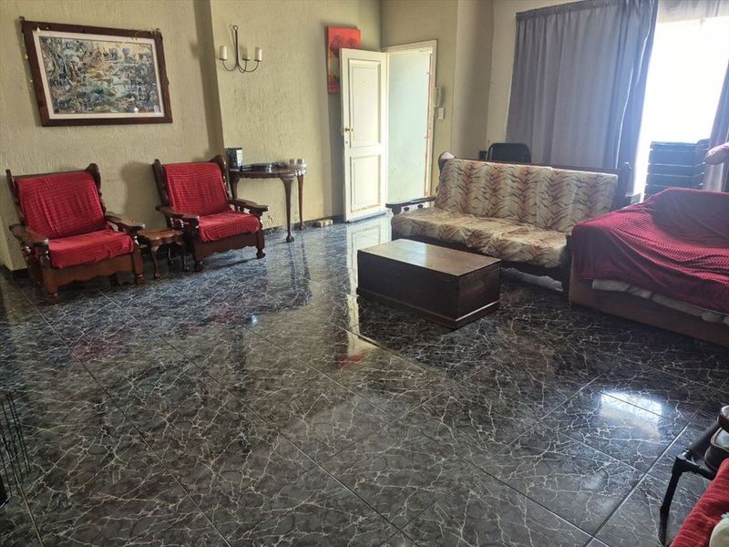 Spacious living room featuring dark marble-effect tiled flooring and textured wall finishes, offering a functional layout with natural light access.