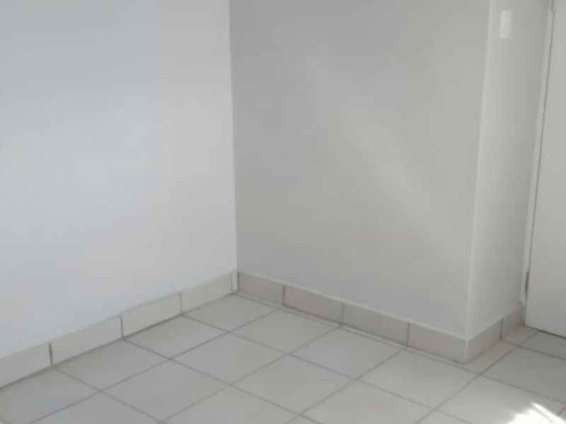 A clean, empty room featuring neutral white walls and light-colored tiled flooring with matching skirting boards.