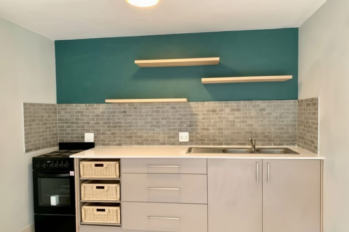 A modern kitchen featuring sleek cabinetry, a subway tile backsplash, floating shelves, and a built-in stove with a clean, contemporary finish.