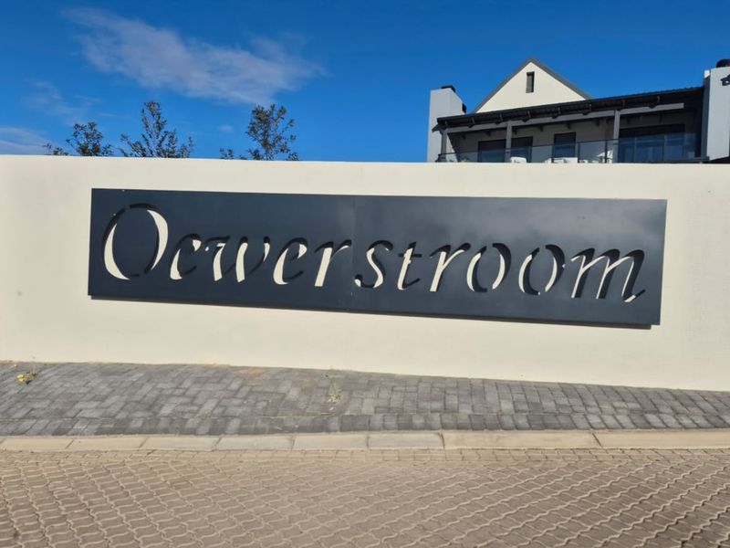 A clear view of the Oewerstroom estate entrance signage featuring a modern boundary wall and paved driveway.