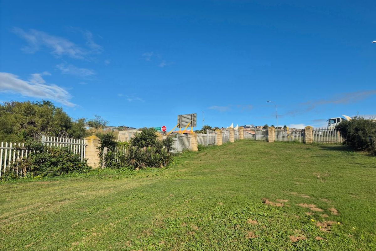 A view of the vacant residential land featuring established grass lawn and secure metal palisade fencing with brick pillars along the perimeter.