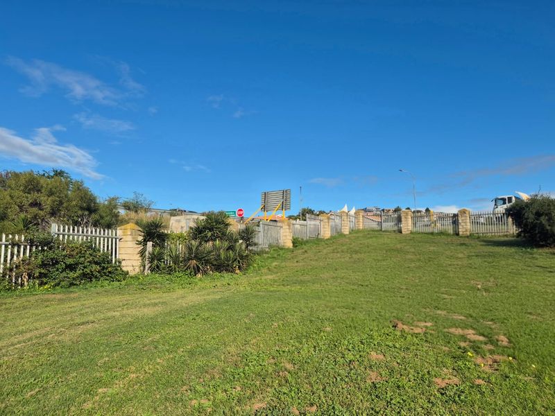 A view of the vacant residential land featuring established grass lawn and secure metal palisade fencing with brick pillars along the perimeter.