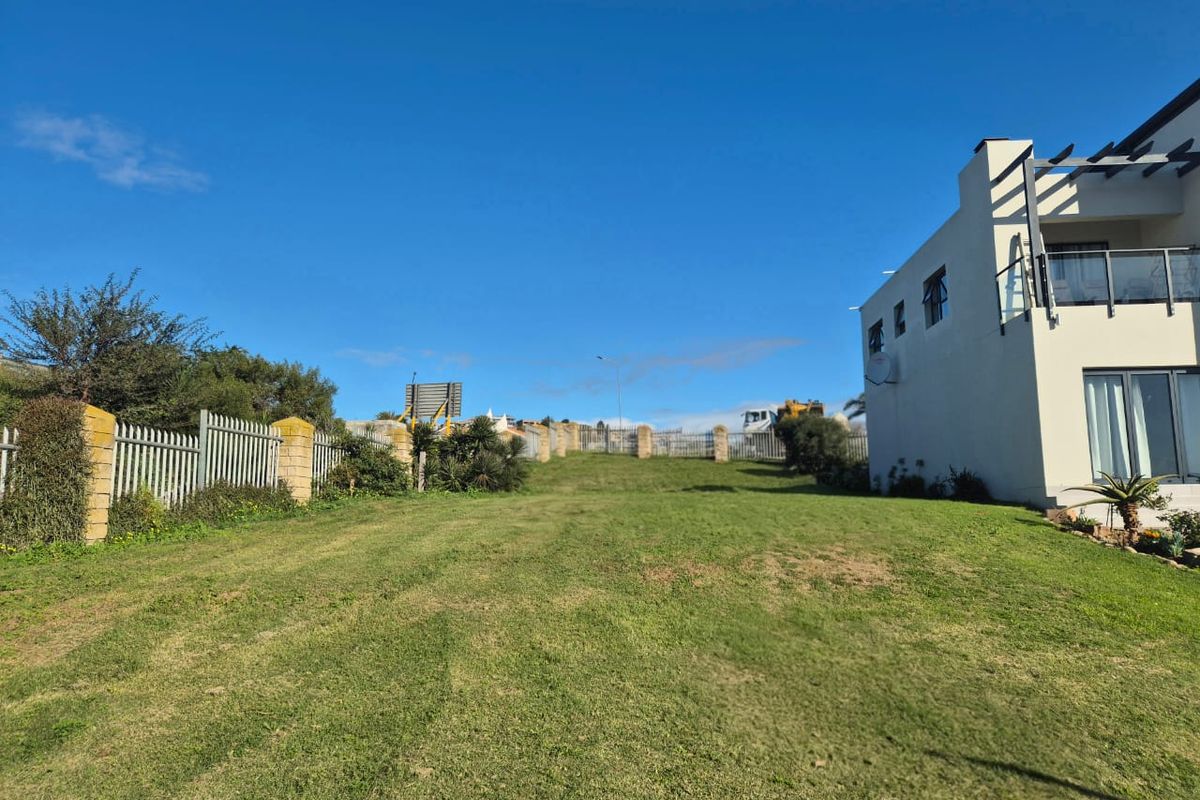 A spacious, well-maintained grassy backyard area featuring perimeter fencing and a view of the adjacent residential structure.