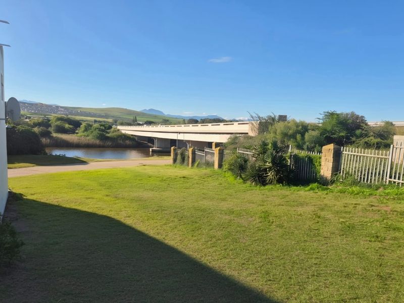 A scenic view of a river, bridge, and surrounding landscape from the property, featuring a well-maintained lawn and perimeter fencing.