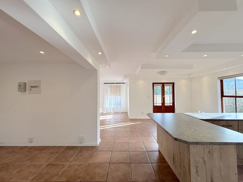 Spacious open-plan living area featuring tiled flooring, recessed ceiling lighting, and a central kitchen island, offering a bright and versatile layout.