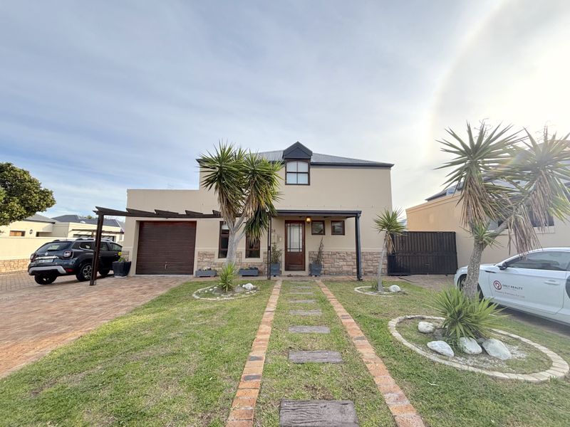 Front elevation of a two-story house featuring stone cladding, a paved driveway, a single garage, and a landscaped front garden with a brick pathway.