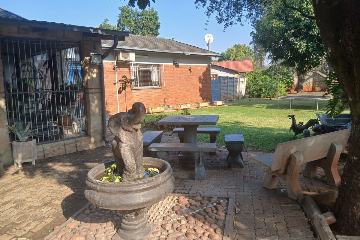 Rear exterior view featuring a brick facade, paved patio area with a stone fountain, and established garden space.