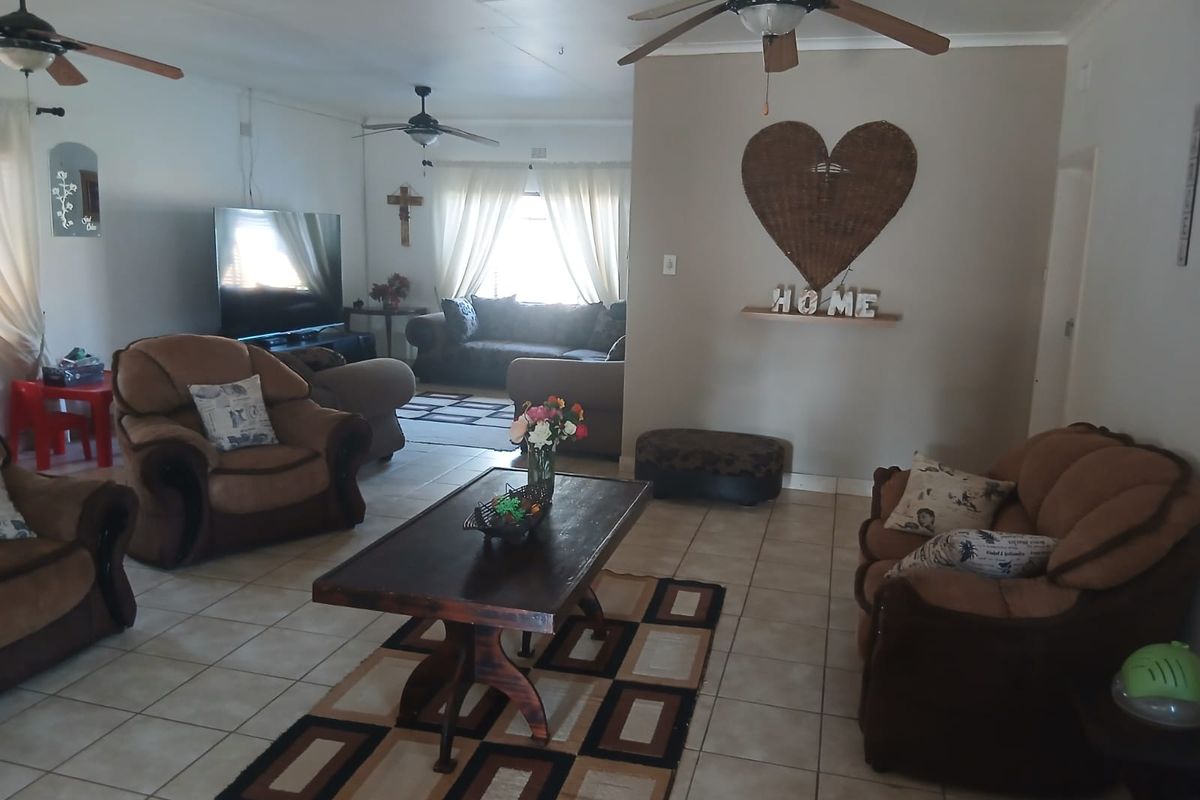 Spacious living room featuring tiled flooring and multiple ceiling fans, offering a comfortable and functional layout for family relaxation.
