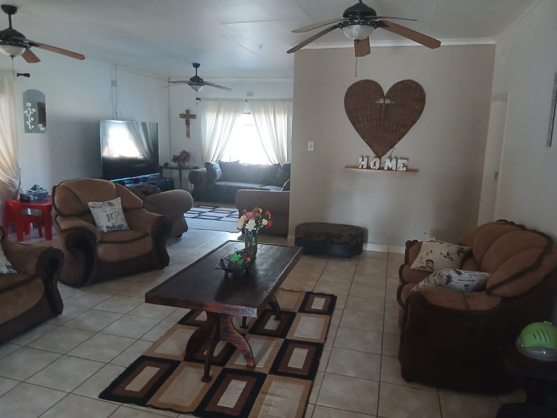 Spacious living room featuring tiled flooring and multiple ceiling fans, offering a comfortable and functional layout for family relaxation.