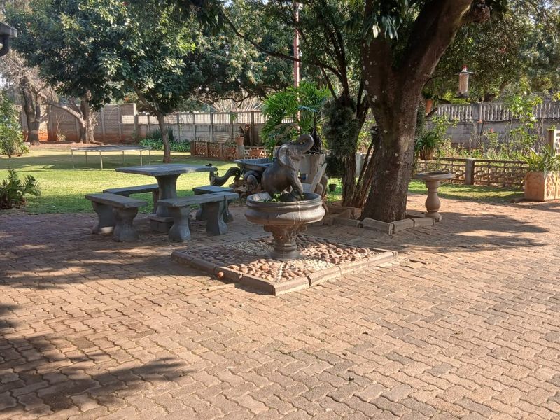 A spacious garden area featuring a paved patio, mature trees, and a boundary wall, providing a private outdoor space.