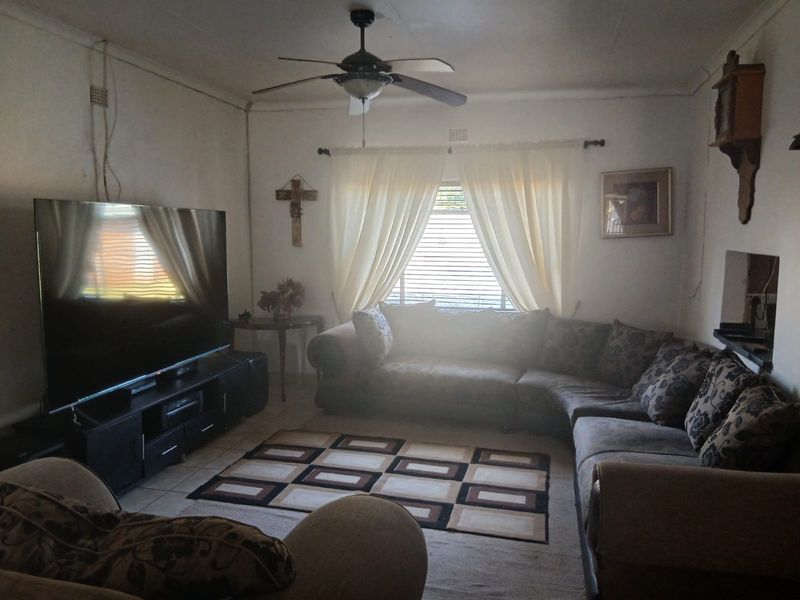 A living room featuring tiled flooring, a ceiling fan, and window blinds, with visible electrical wiring on the wall.