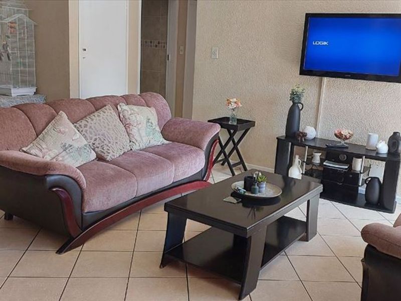 A living room area featuring tiled flooring and textured wall finishes, providing a functional and neutral space for relaxation.