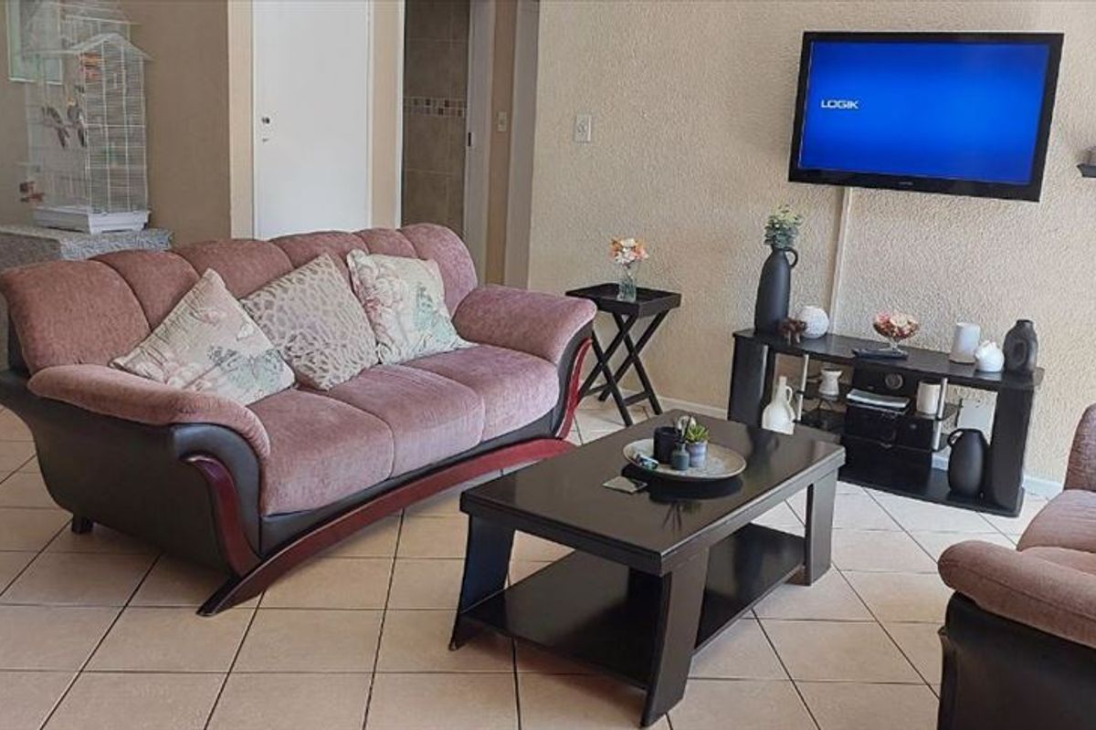 A living room area featuring tiled flooring and textured wall finishes, providing a functional and neutral space for relaxation.
