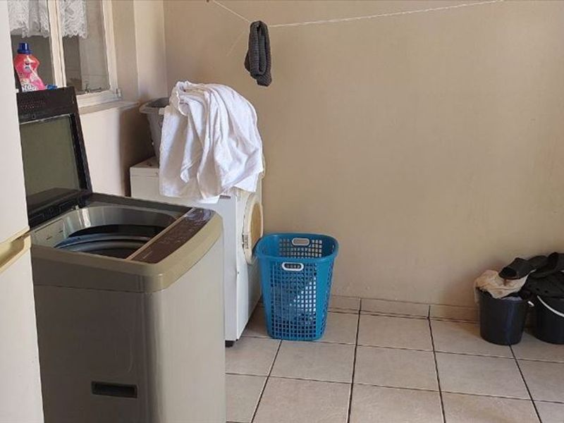 A functional laundry area featuring tiled flooring and dedicated plumbing connections for washing appliances.