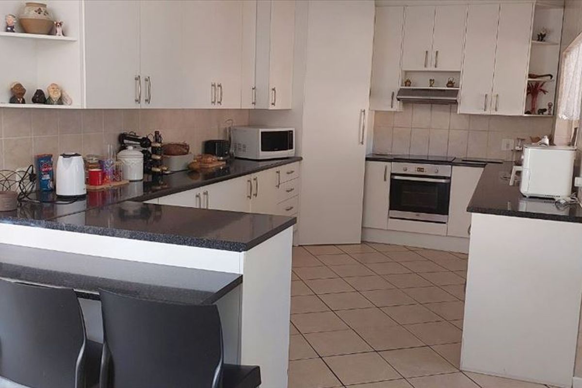Functional kitchen featuring white cabinetry, granite countertops, tiled backsplash, and a breakfast nook, providing a practical layout for daily meal preparation.