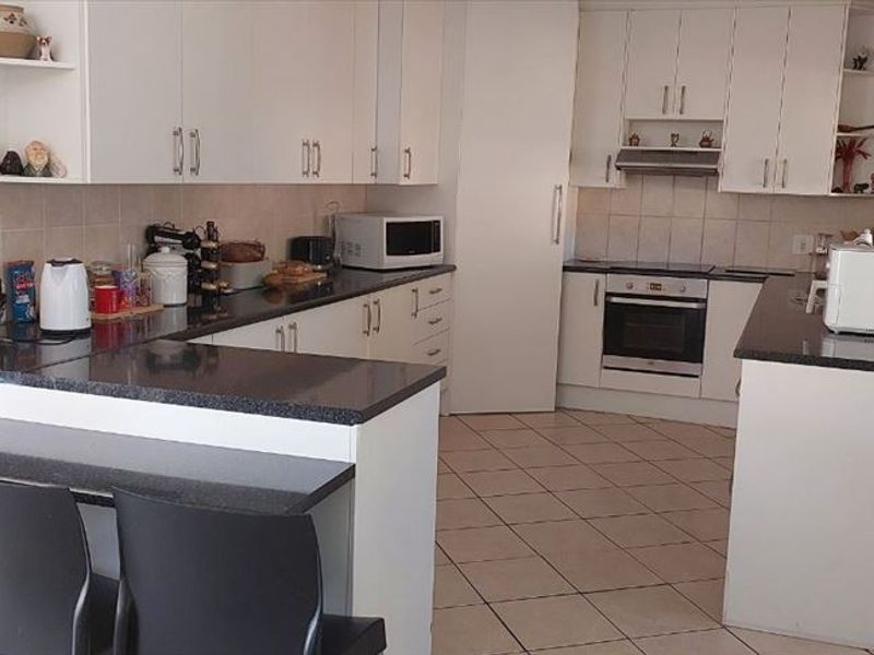 Functional kitchen featuring white cabinetry, granite countertops, tiled backsplash, and a breakfast nook, providing a practical layout for daily meal preparation.
