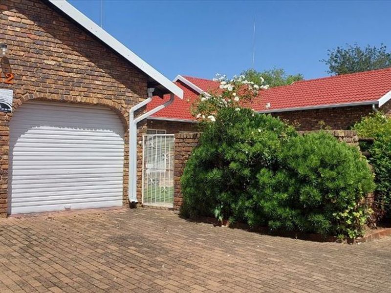 Front exterior view of a face brick townhouse featuring a double garage with roll-up doors and a paved driveway.