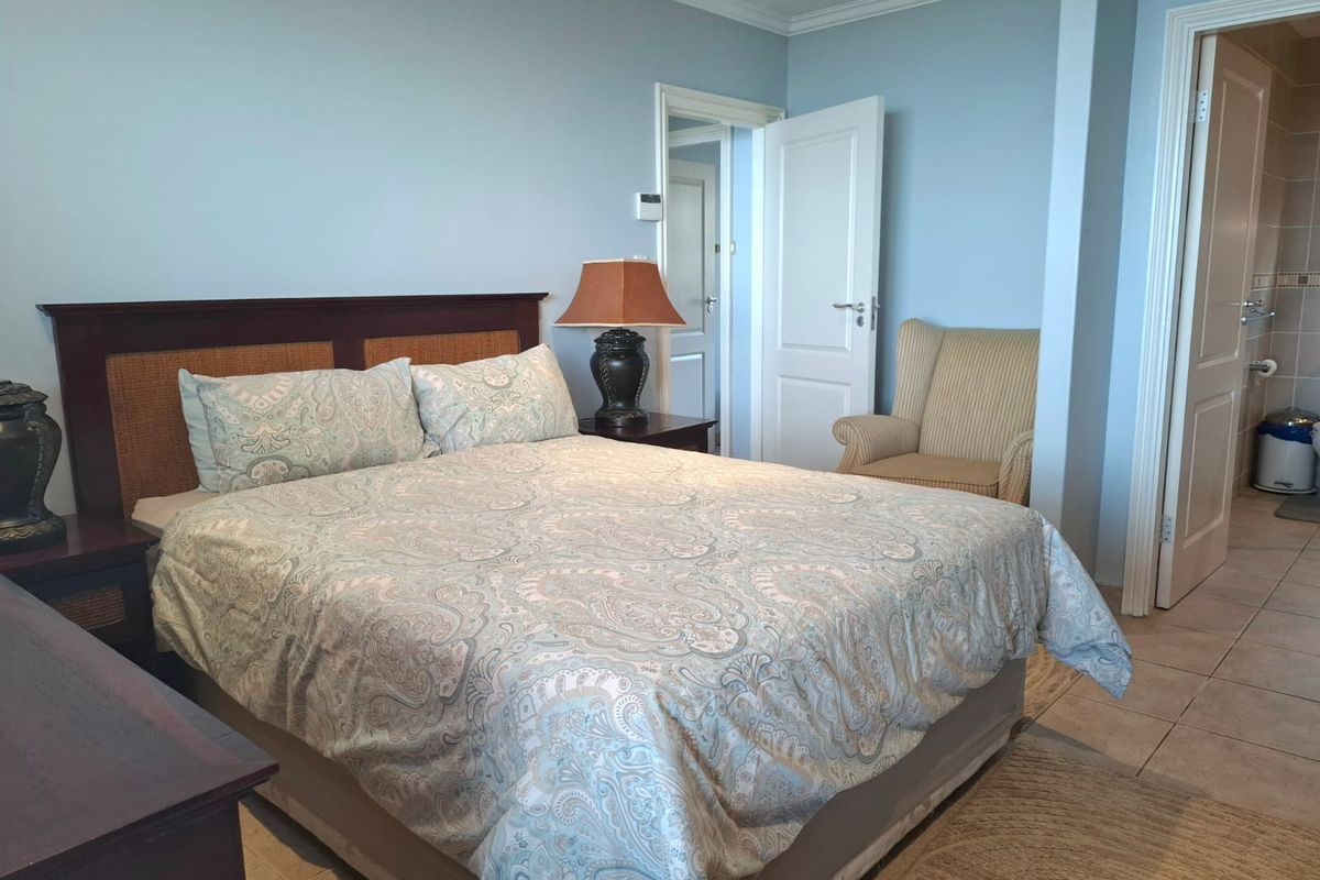 A well-maintained bedroom featuring tiled flooring, crown molding, and direct access to an en-suite bathroom.