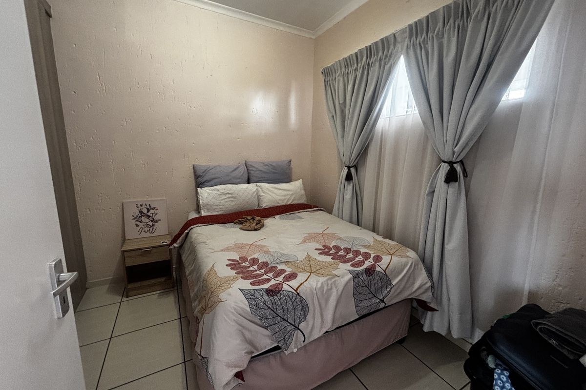 A compact bedroom featuring tiled flooring and a built-in cupboard, providing a functional sleeping space with neutral wall finishes.