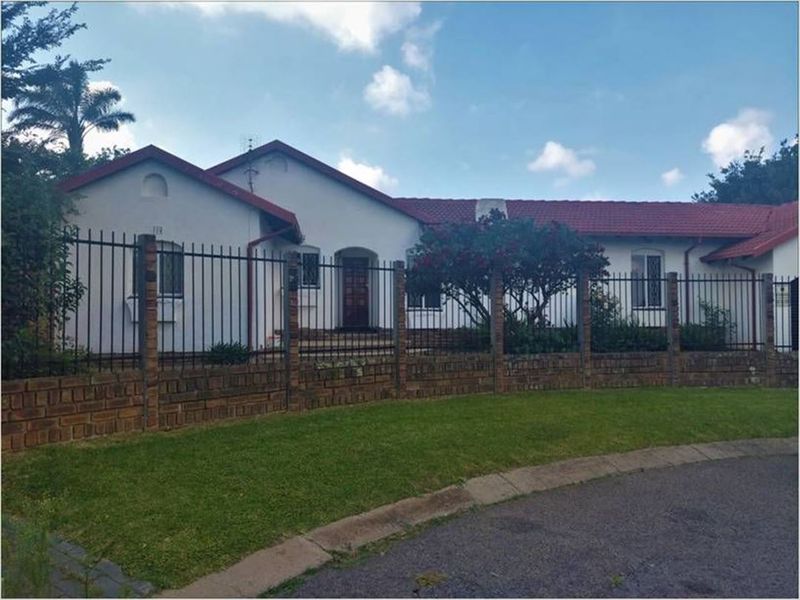 Front elevation of a single-story house featuring a tiled roof, brick boundary wall, and secure wrought iron fencing.