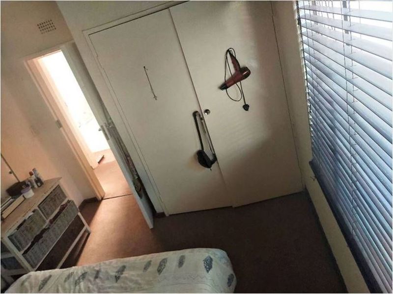 A bedroom featuring a built-in wardrobe and venetian blinds, offering a functional space with standard finishes.