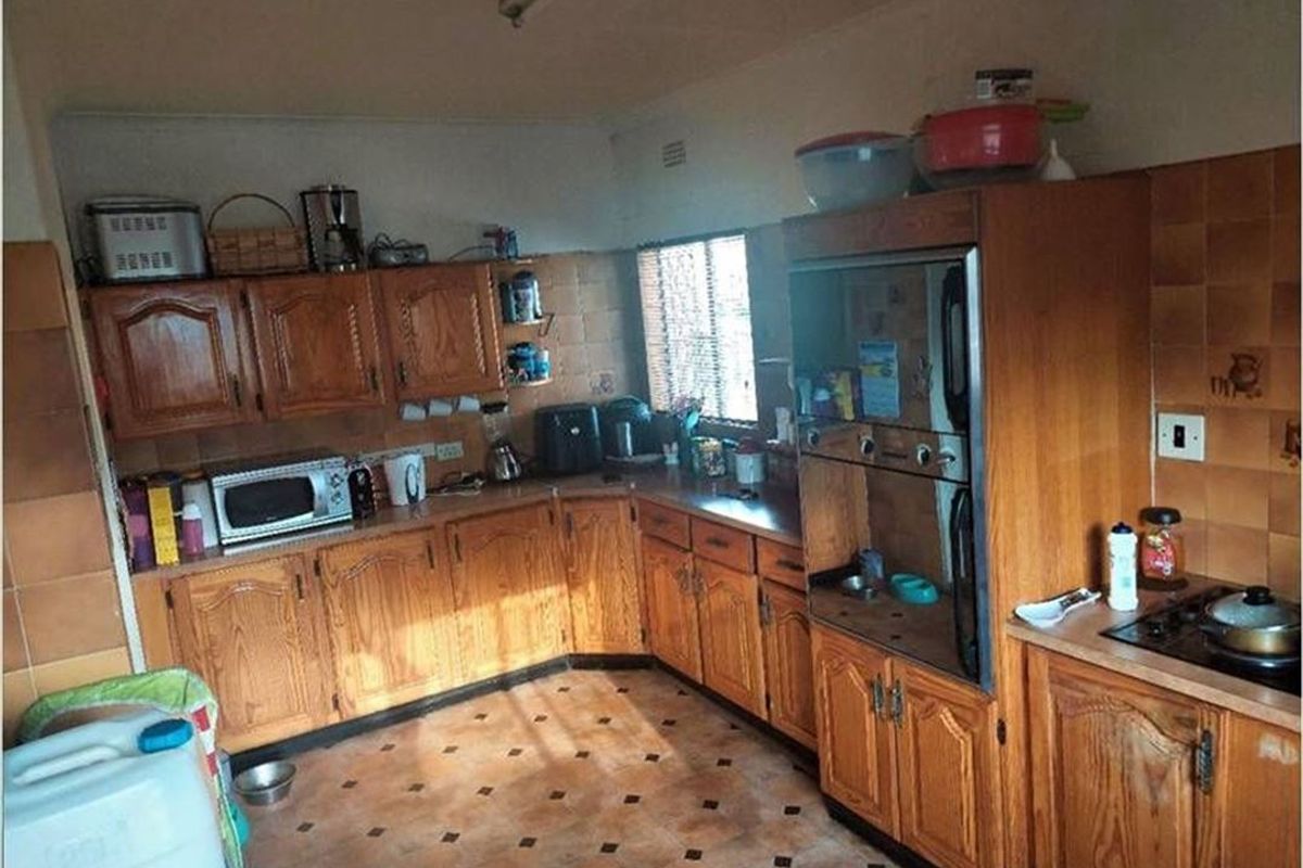 A dated kitchen featuring wooden cabinetry, built-in oven, hob, and tiled finishes, offering significant potential for a modern renovation.