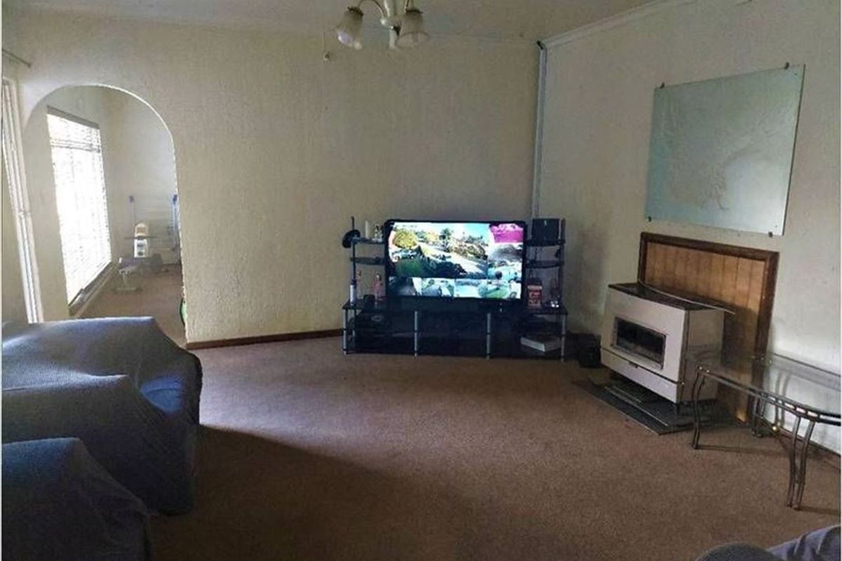 A living room featuring a built-in fireplace, arched doorway leading to an adjacent space, and carpeted flooring.